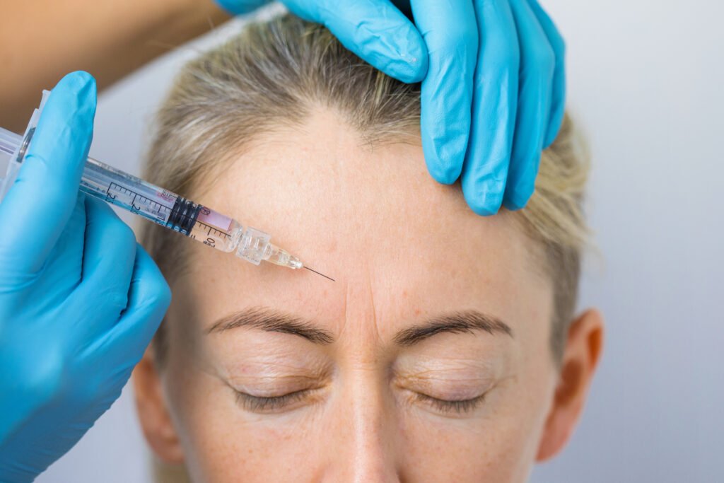 Face of a woman during botox treatment to smooth expression lines. Concept of anti-aging and rejuvenation cosmetics on forehead wrinkles | Neuromodulators | The Aesthetic dmc in Tucson, AZ